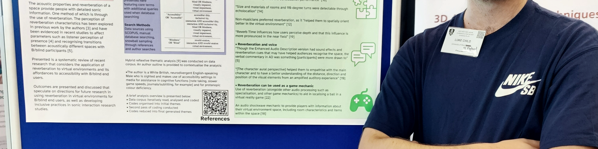 A close up of Luke at a conference power posing in front of an academic poster displaying his work.